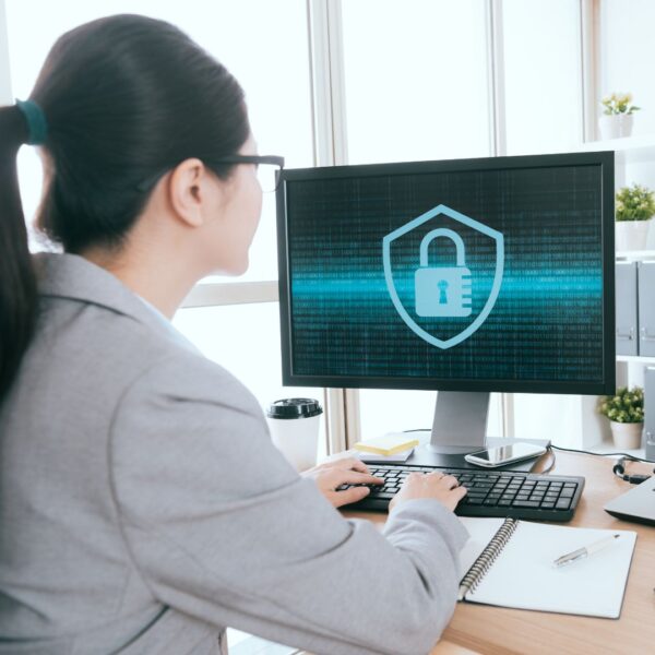 Woman working at a desktop computer with a security graphic on it. 